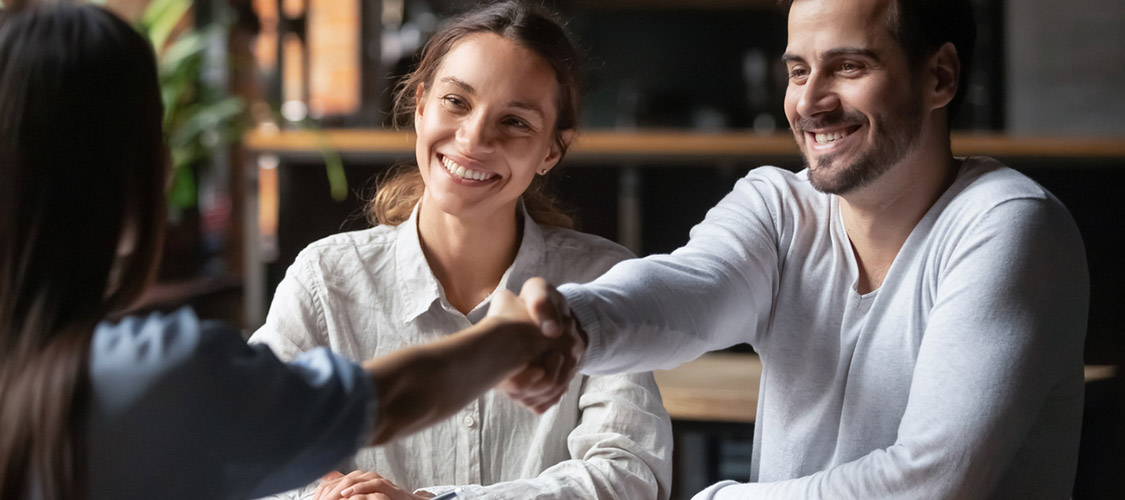 agent shaking hands with happy clients