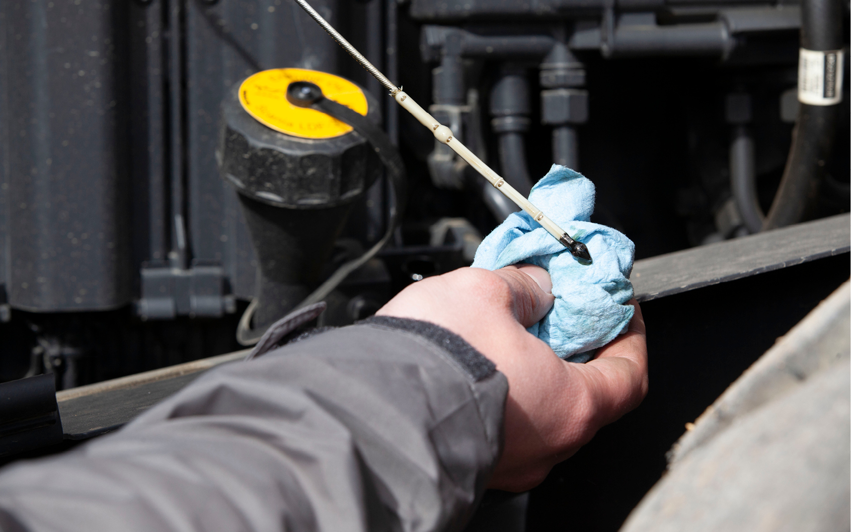 An operator checks the machine’s engine oil by examining the dipstick.