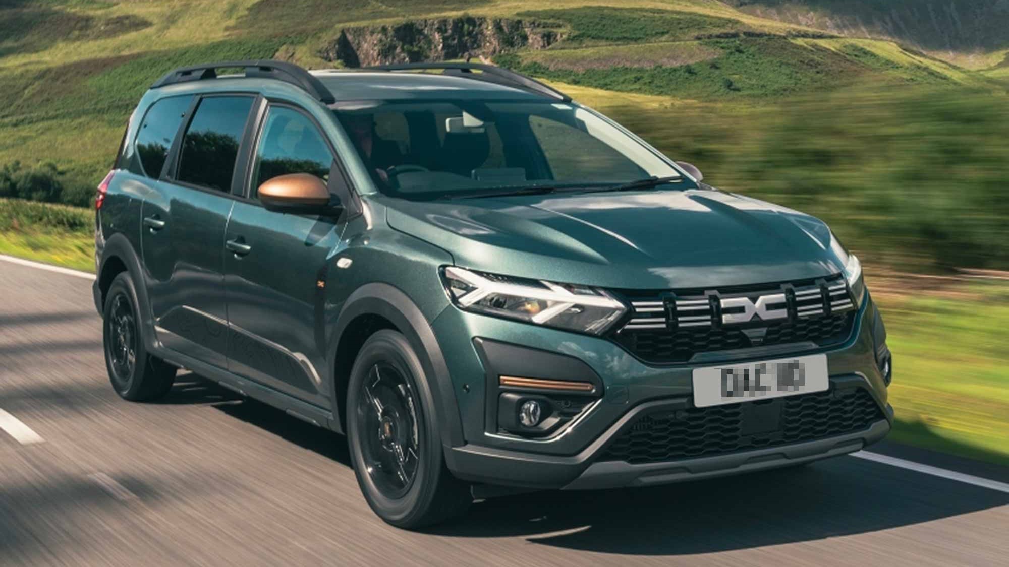 A dark green Dacia Jogger driving on a countryside road