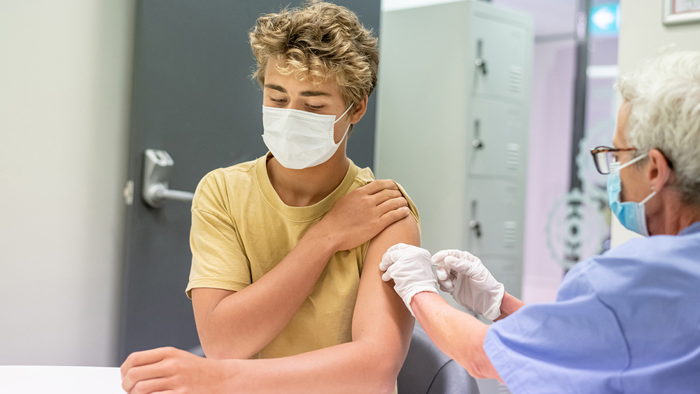A picture of a health worker vaccinating a woman. Both have masks on.
