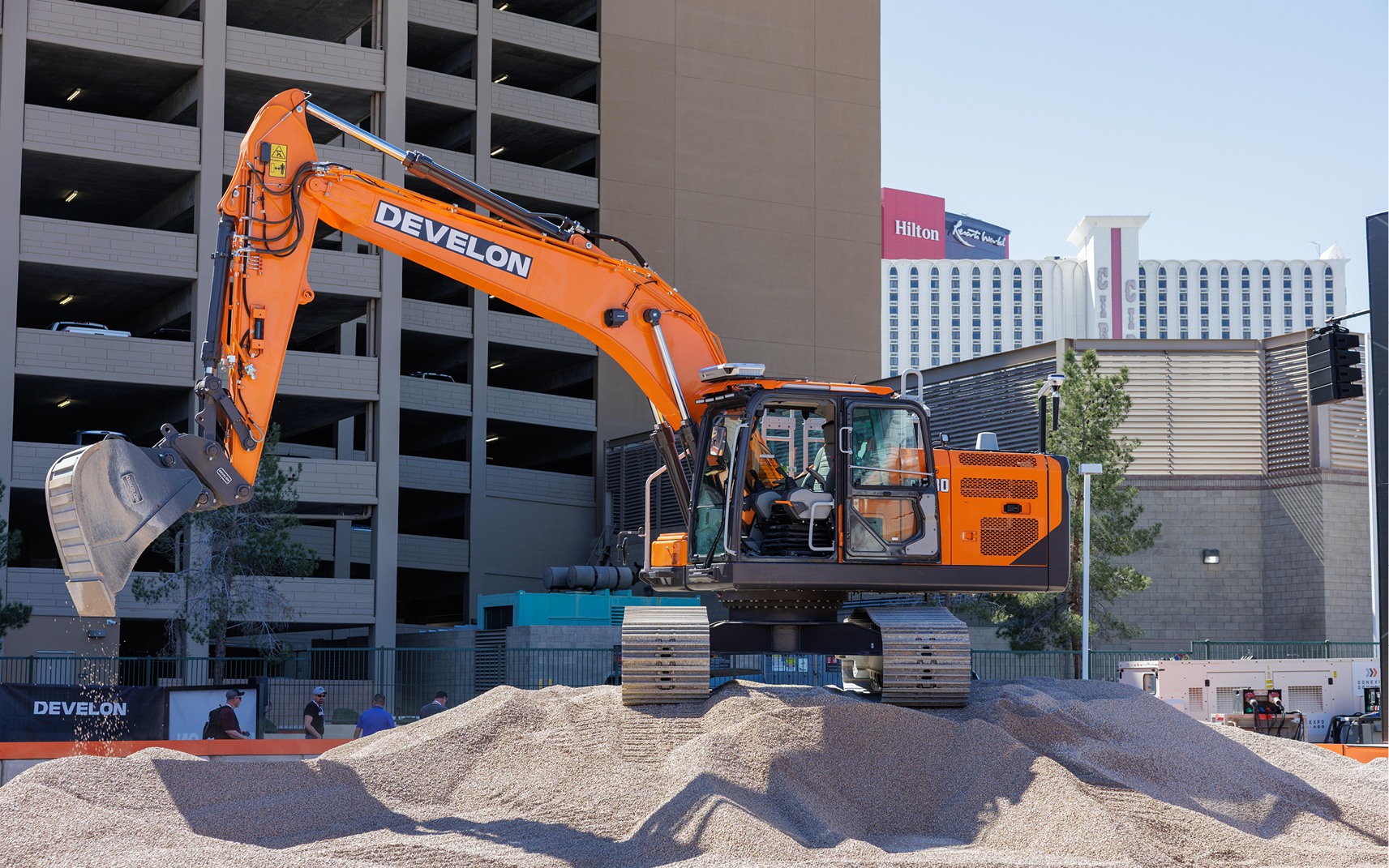 The -9 Series DX230LC-9 crawler excavator dumping gravel in the demonstration area of the DEVELON booth at CONEXPO 2026.