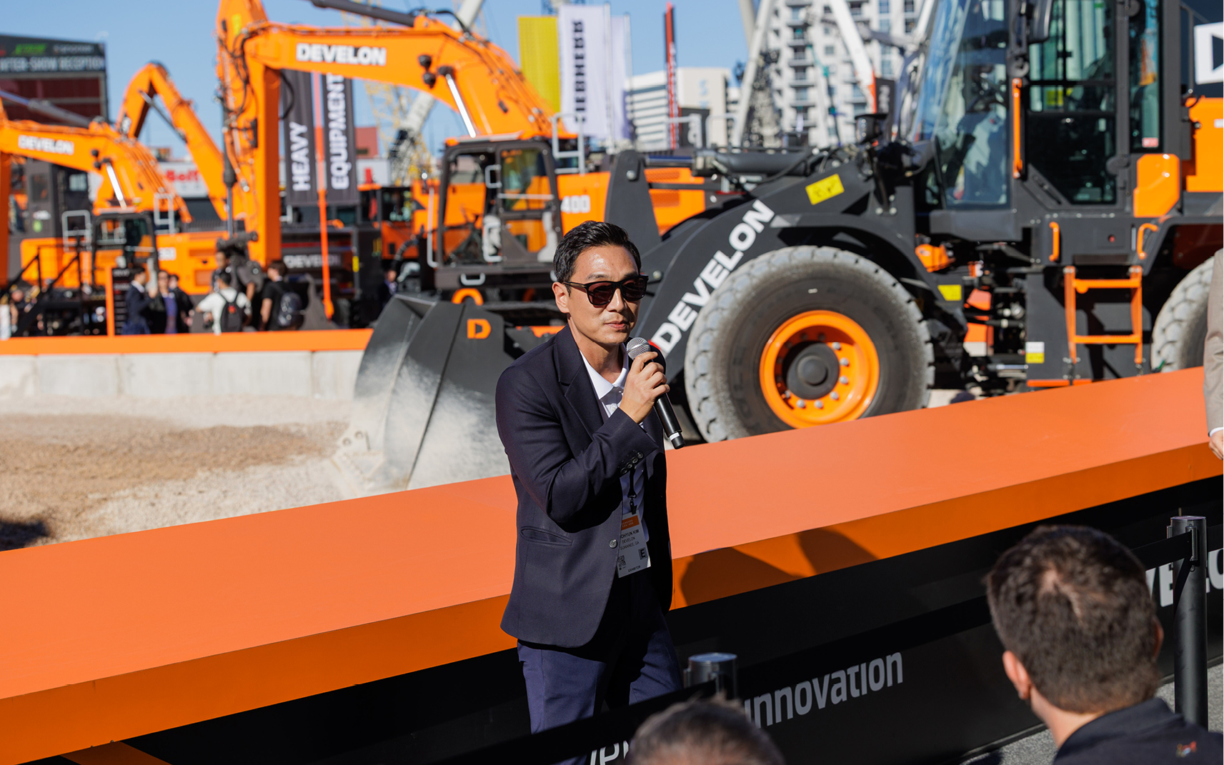 DEVELON CEO WH Kim delivering opening remarks to a crowd at the -9 Series crawler excavator press event at CONEXPO 2026.