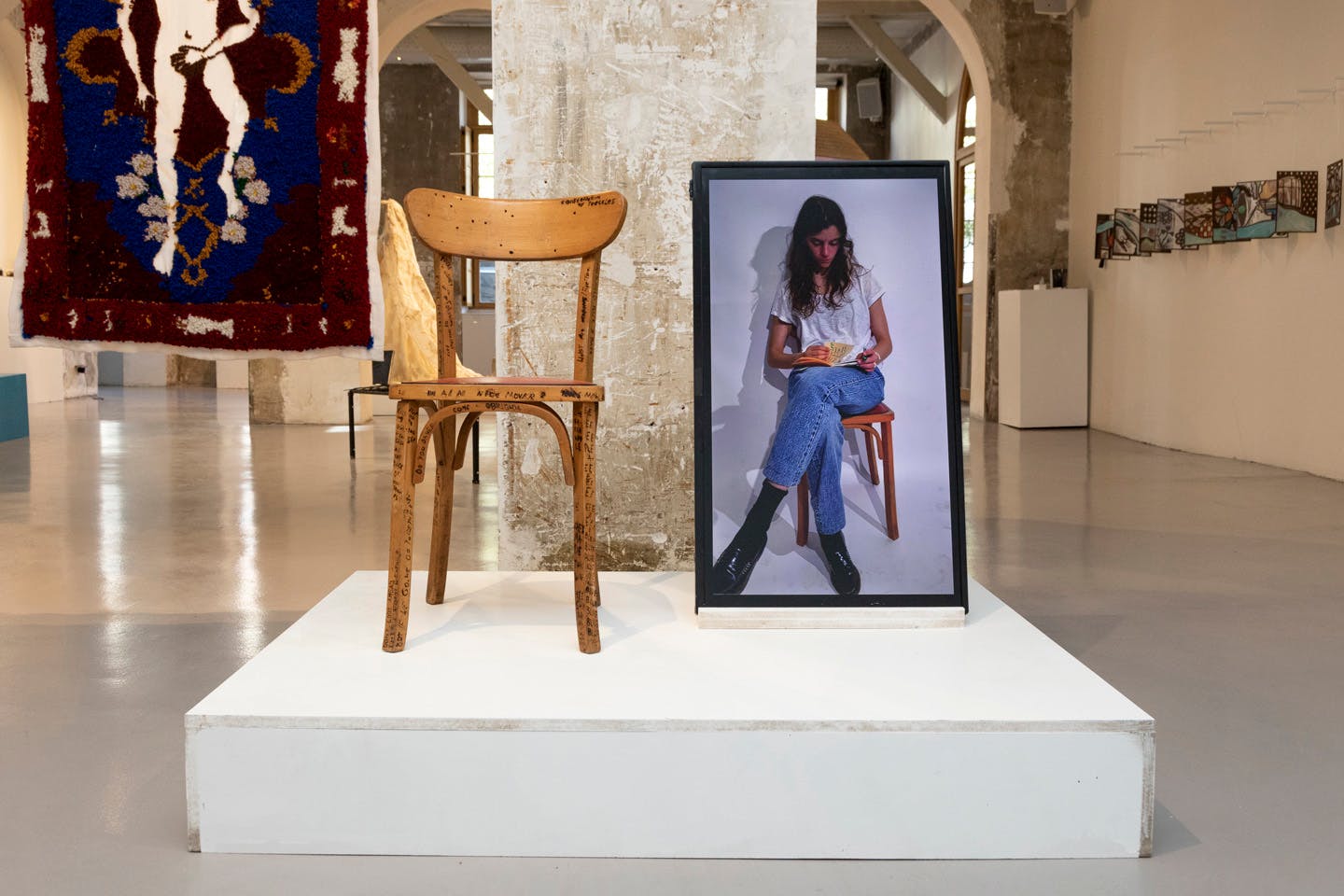Wooden chair beside framed portrait of woman reading a book