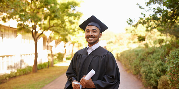 student holding his diploma in his a graduation gown