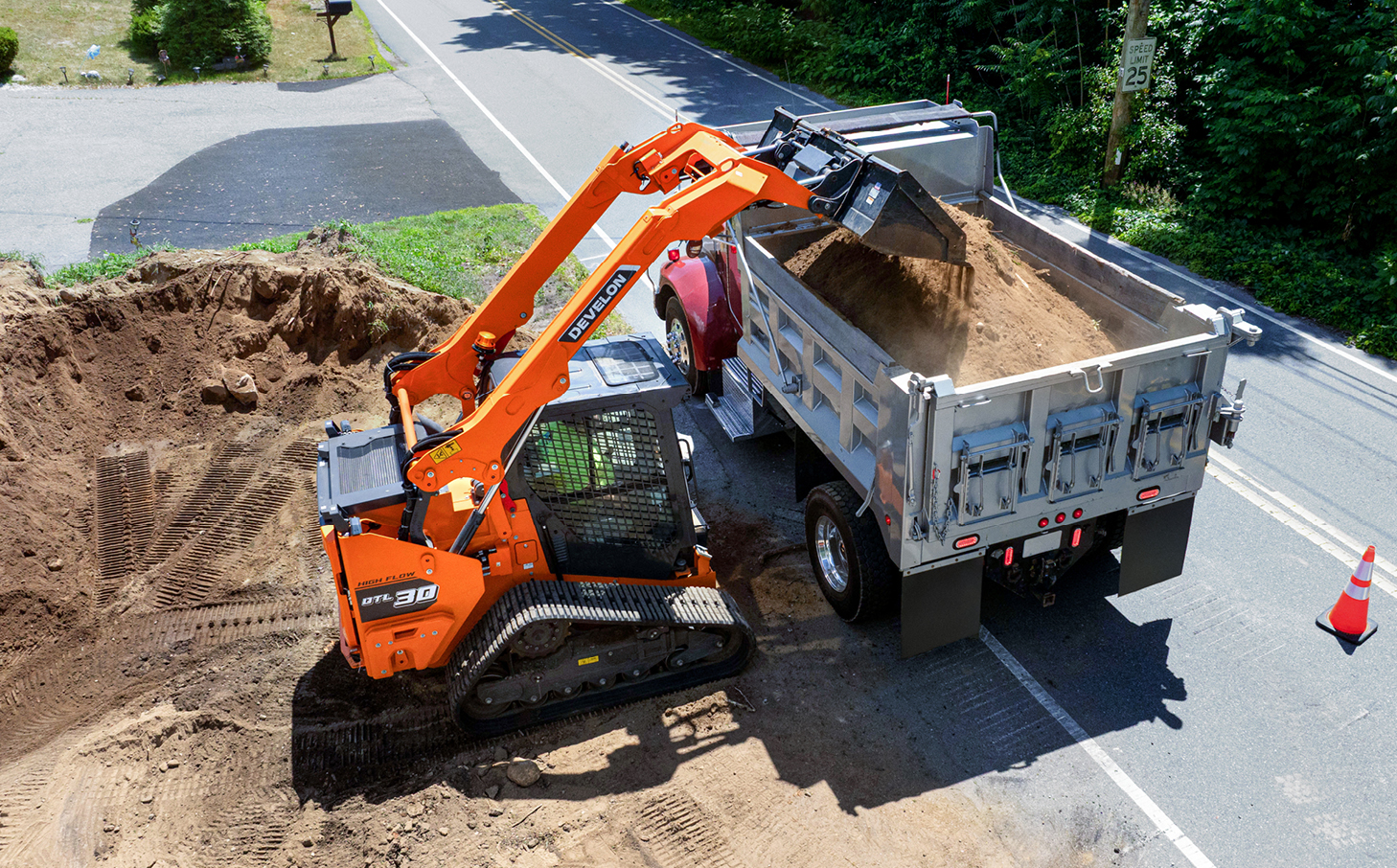 The new DEVELON DTL30 compact track loader dumps dirt into a dump truck on a residential jobsite.