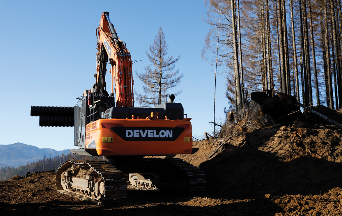 A DEVELON road builder moves timber on a job site.