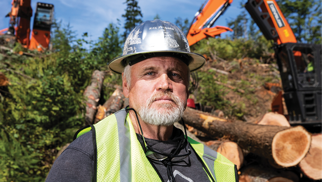 Owner of McLaughlin Logging standing in front of forestry machines.