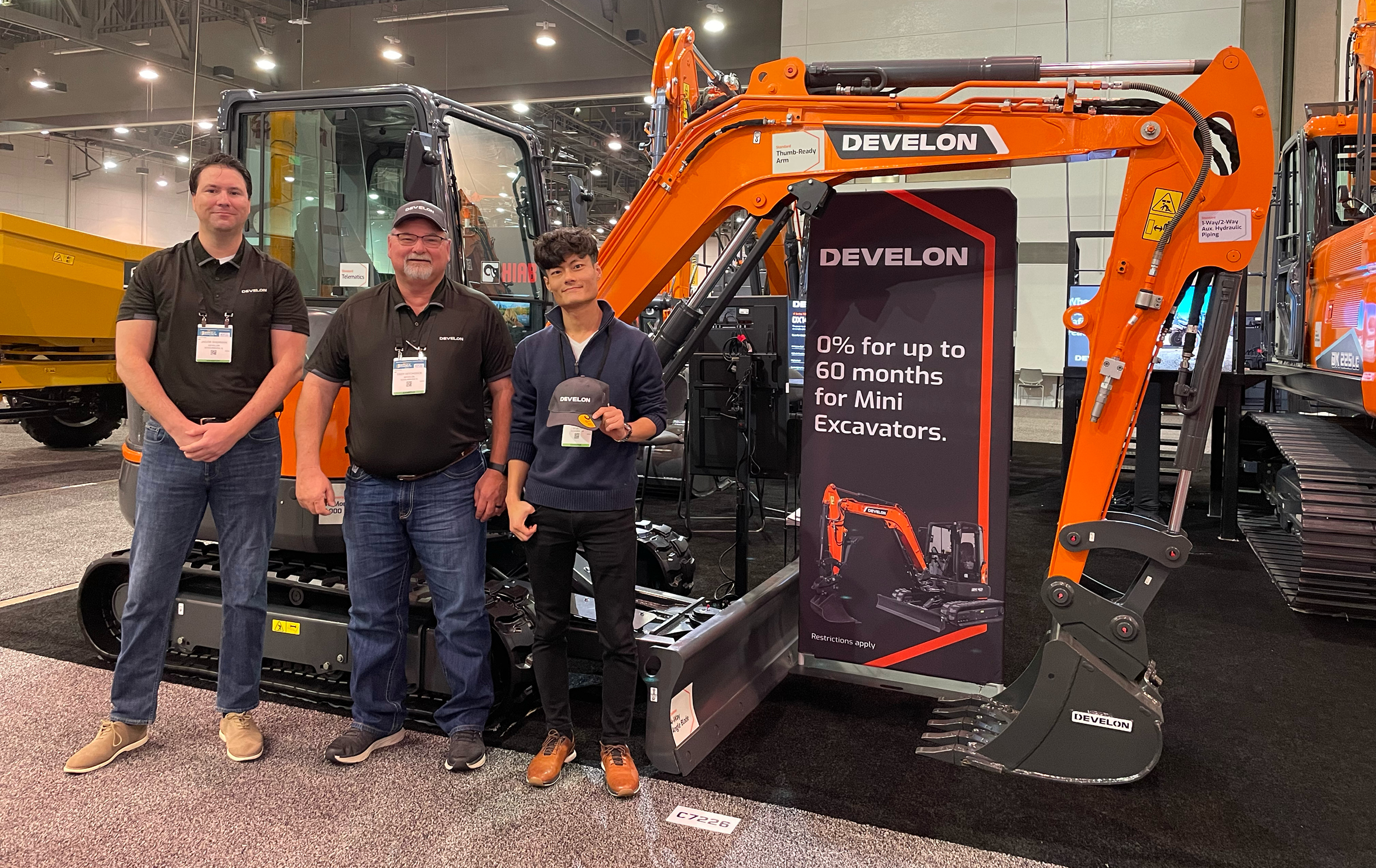 Three DEVELON representatives in front of DX42-7 Mini Excavator.