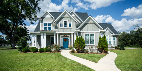 A lovely two-story house with gray vinyl siding surrounded by a well manicured lawn
