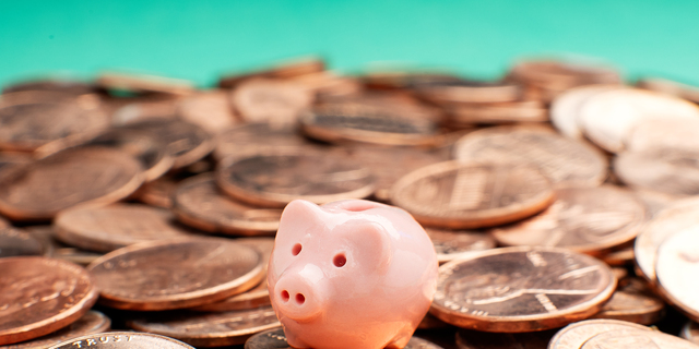 Savings concept - Tiny piggy bank on pennies