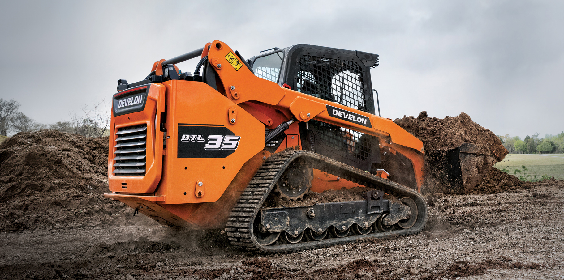 The DEVELON DTL35 compact track loader hauling dirt on a job site.