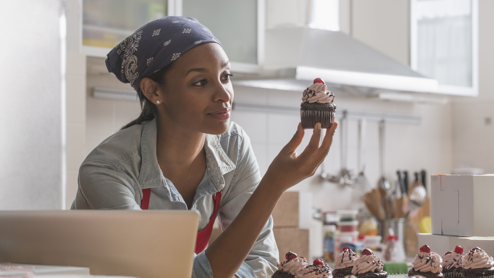 Mixed race baker admiring cupcake in commercial kitchen