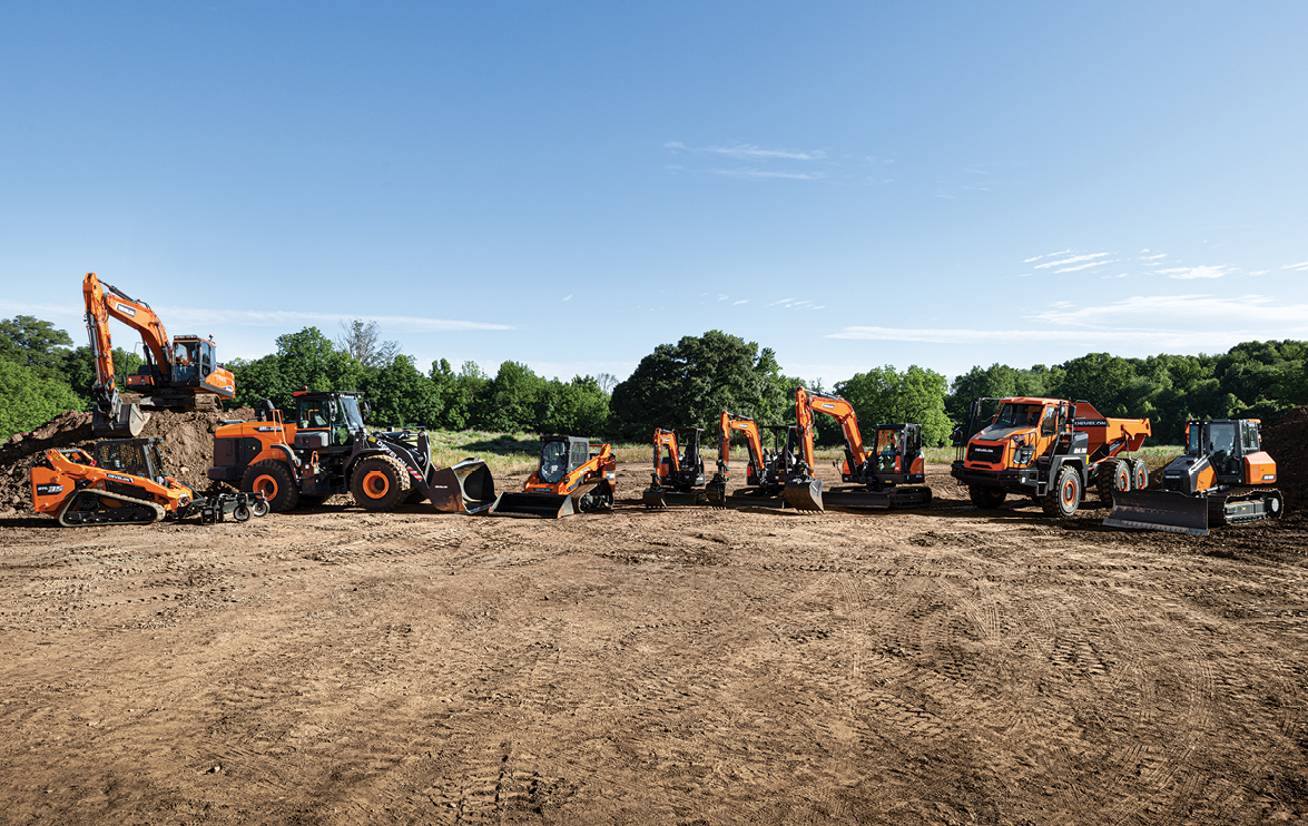 A lineup of DEVELON construction equipment—including excavators, wheel loaders, compact track loaders, an ADT, and a dozer—parked on a dirt jobsite.