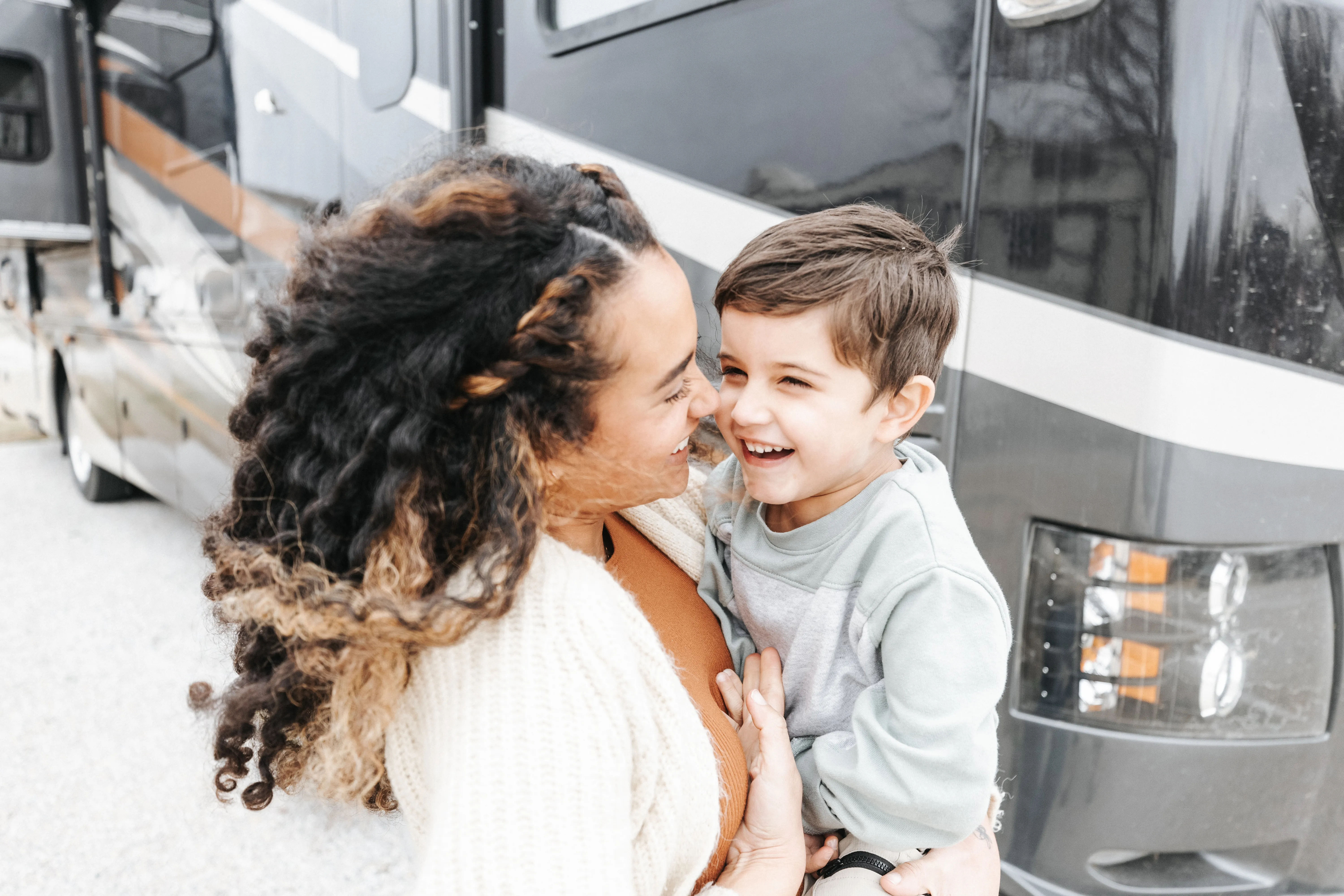 Mom and young son standing by RV, sharing a laugh. 