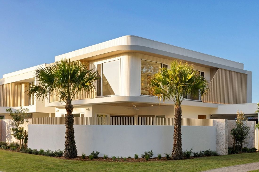 Two storey house on a corner block with large palm trees.