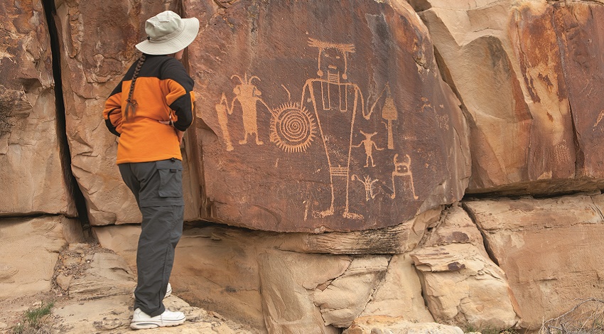 A woman looking at the McKee Spring petroglyphs