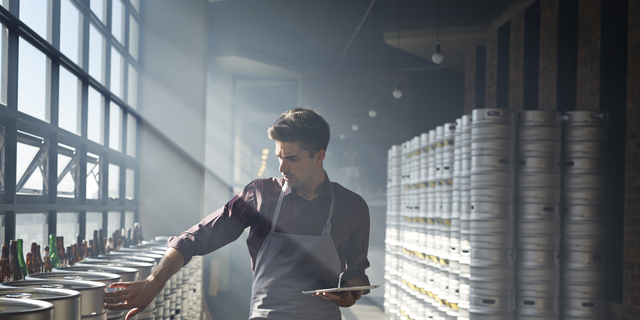 Bartender counting beer keg's and using tablet