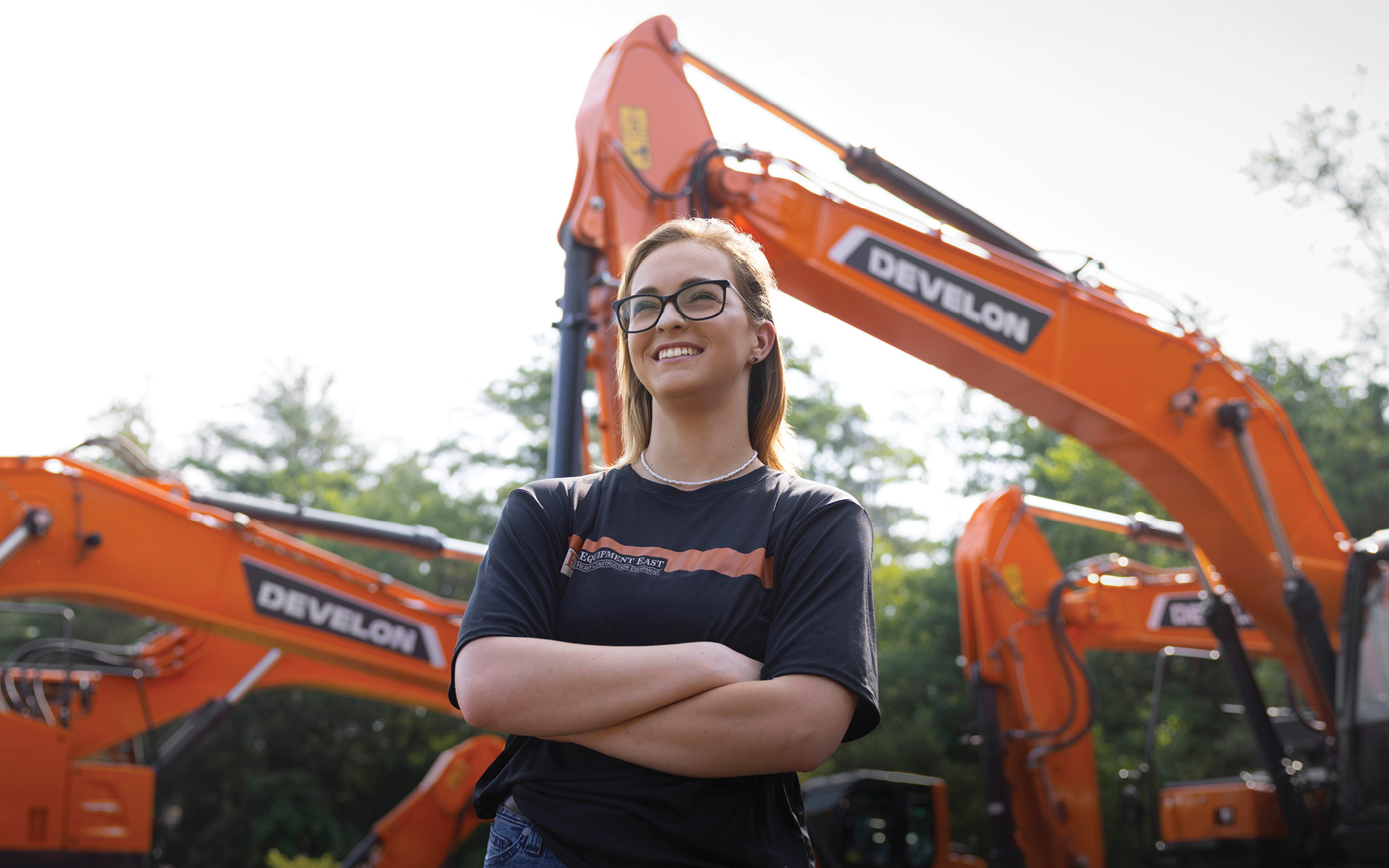 Emily Paquette of Equipment East standing in front of a fleet of DEVELON equipment.