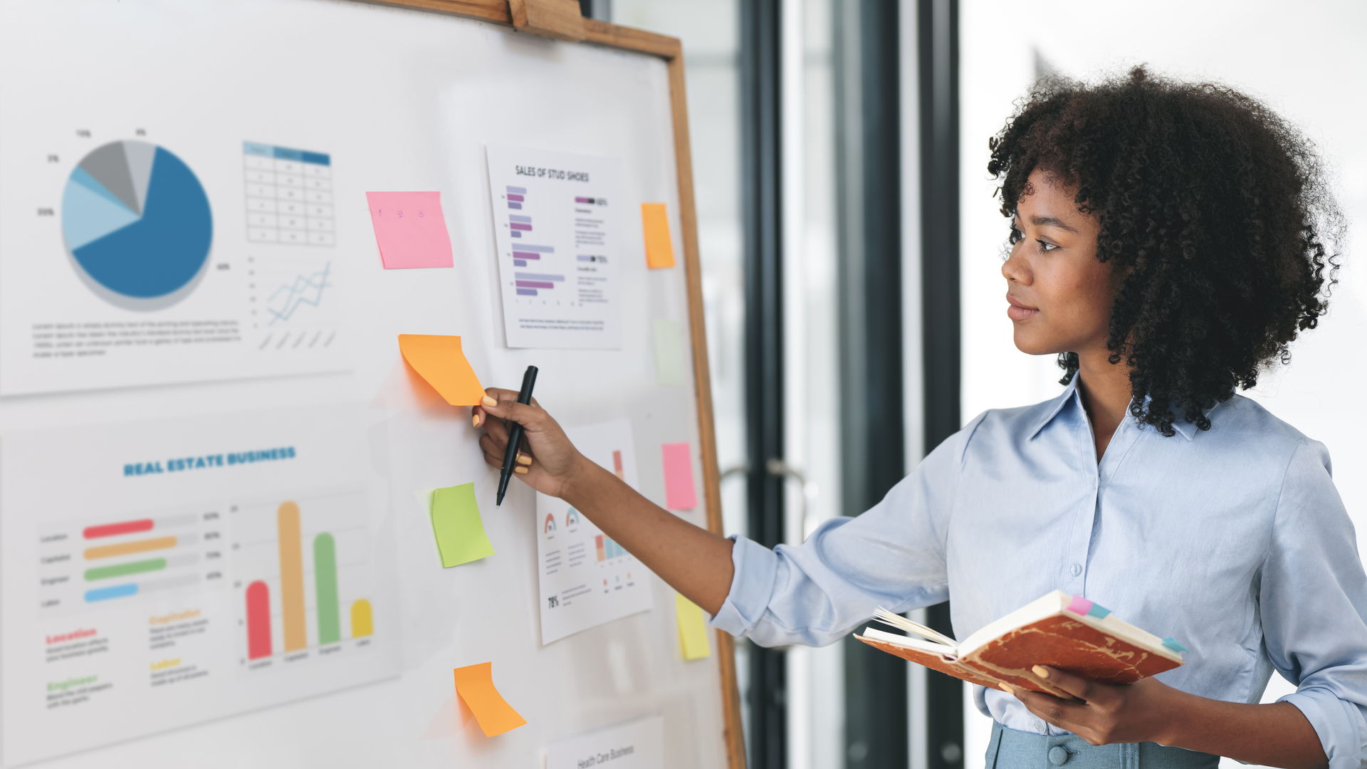 Young creative ethnic businesswoman working on sticky note on board, planning analyzing business finance and marketing at office.