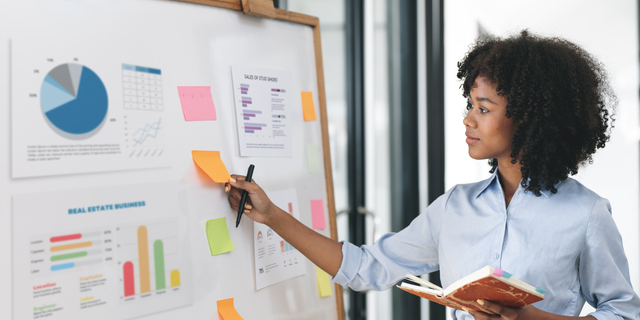 Young creative ethnic businesswoman working on sticky note on board, planning analyzing business finance and marketing at office.