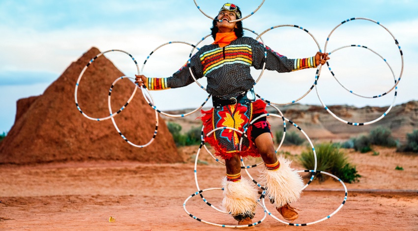 A Native American dancer performing a hoop dance with multiple hoops