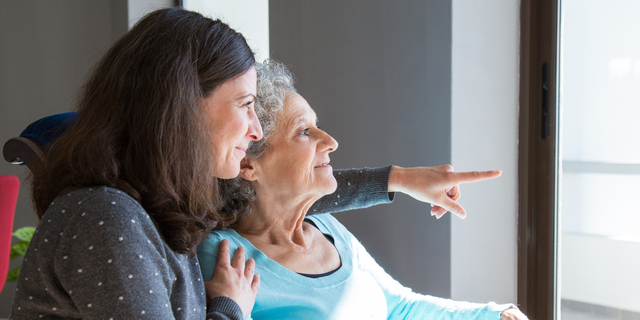 Happy senior mother and adult daughter enjoying dramatic view