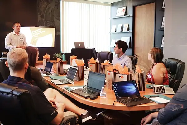 Engaged team sitting around conference table with speaker presenting