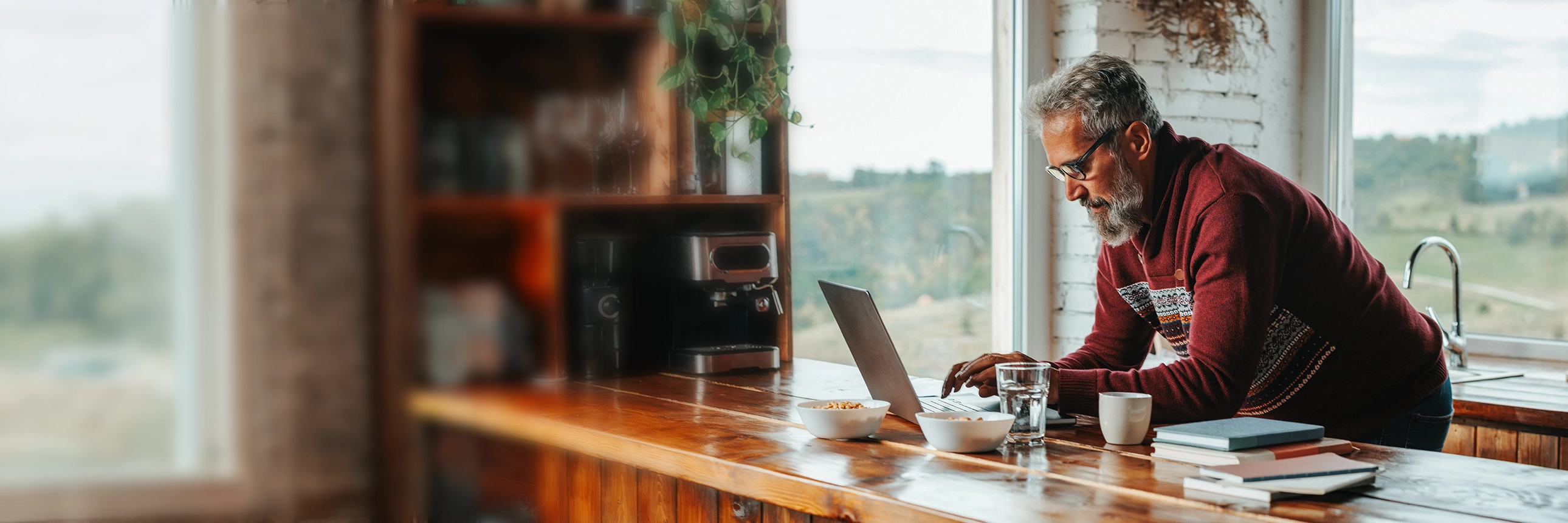 Person using a laptop at a kitchen counter in a home setting.
