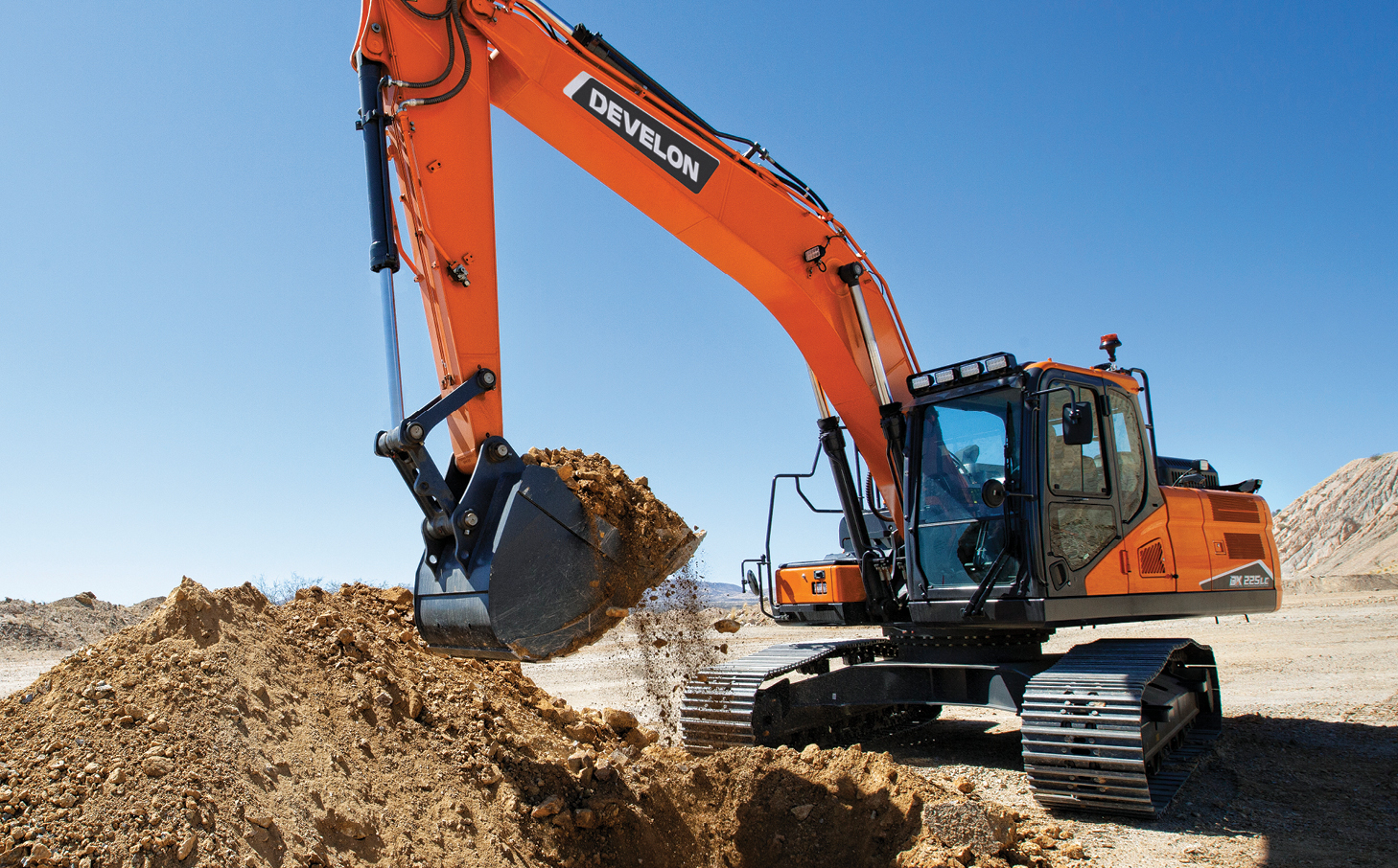A DEVELON crawler excavator digging dirt on a job site.