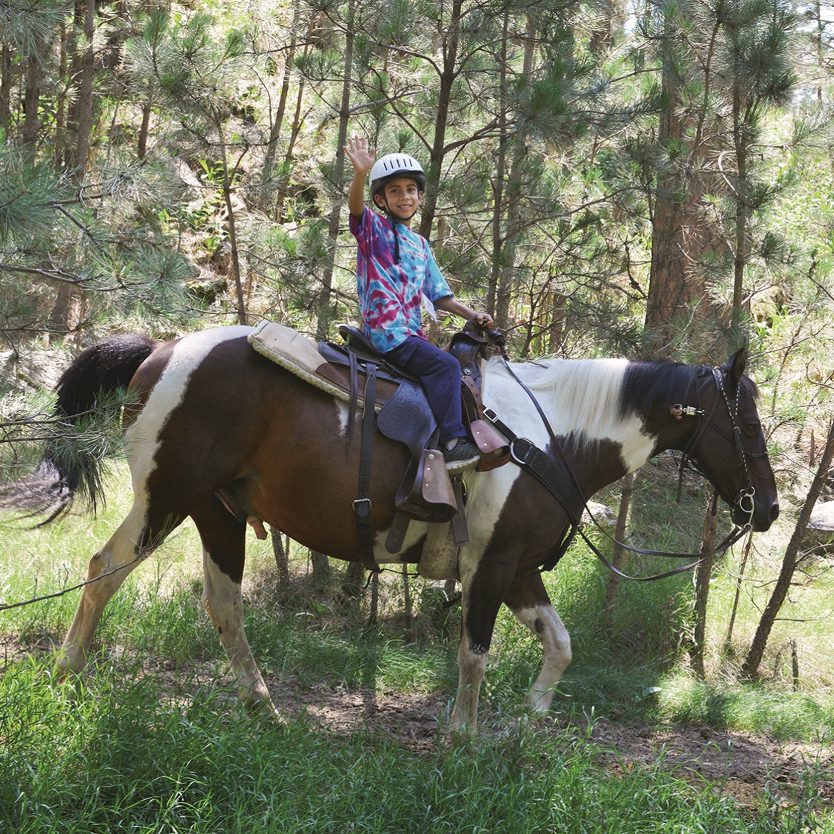 A grandkid waving from a trail ride in South Dakota