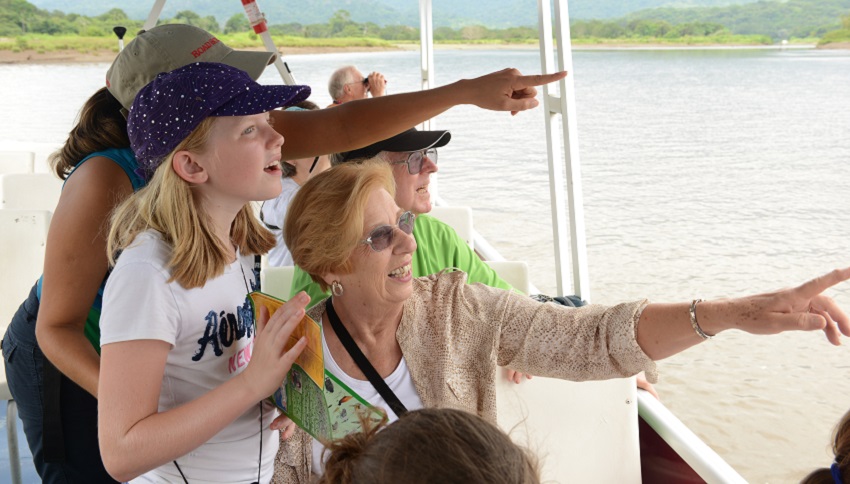 Grandparents and grandkids point at a sight on a boat ride in Costa Rica