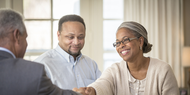 African American couple shaking hands with businessman