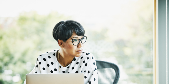 Portrait of mature businesswoman working on laptop at workstation in office