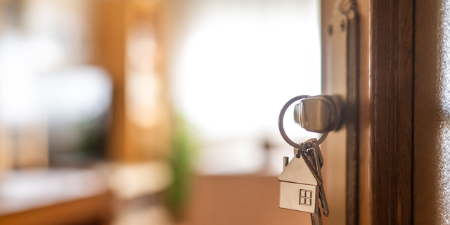 House-shaped keys are hanging from the door knob of a new home, representing the exciting moment of acquiring property and starting a fresh chapter