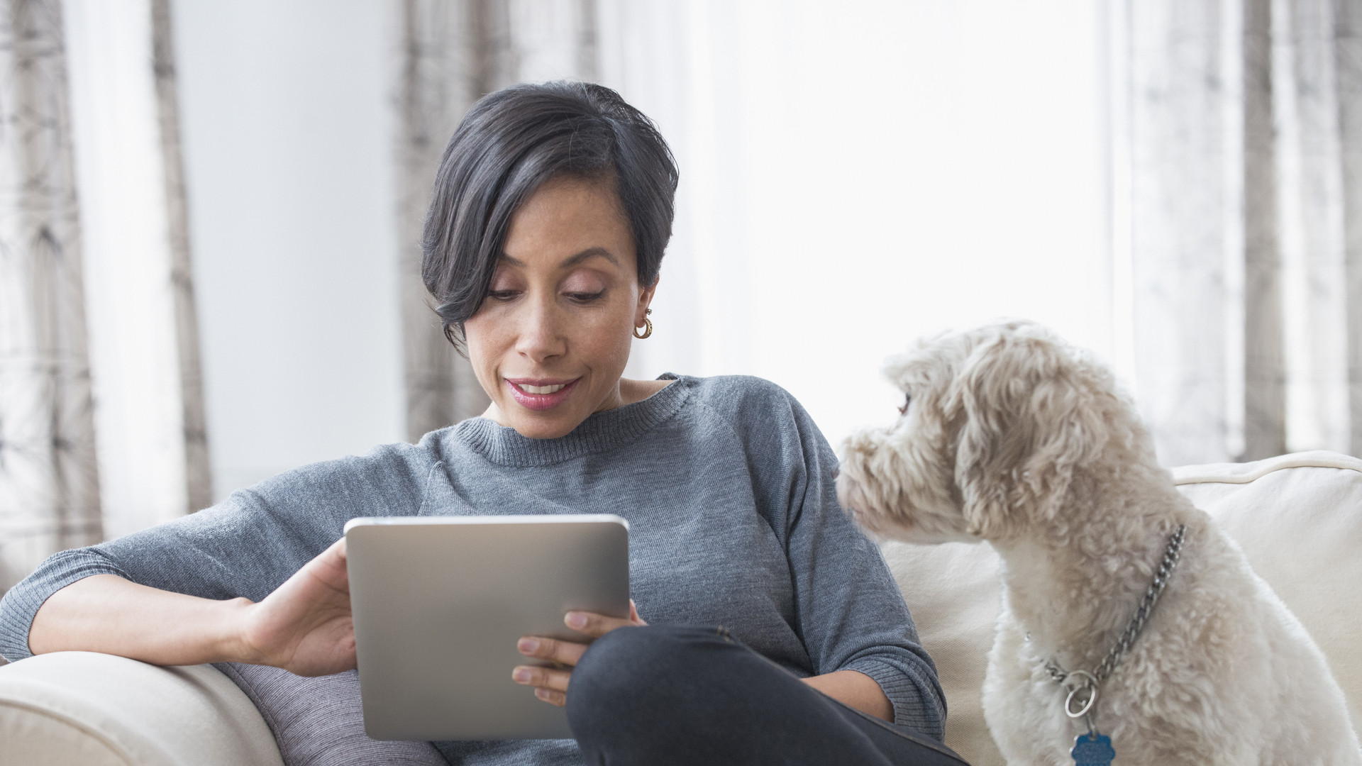 Black woman using digital tablet with dog