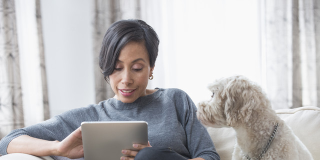 Black woman using digital tablet with dog