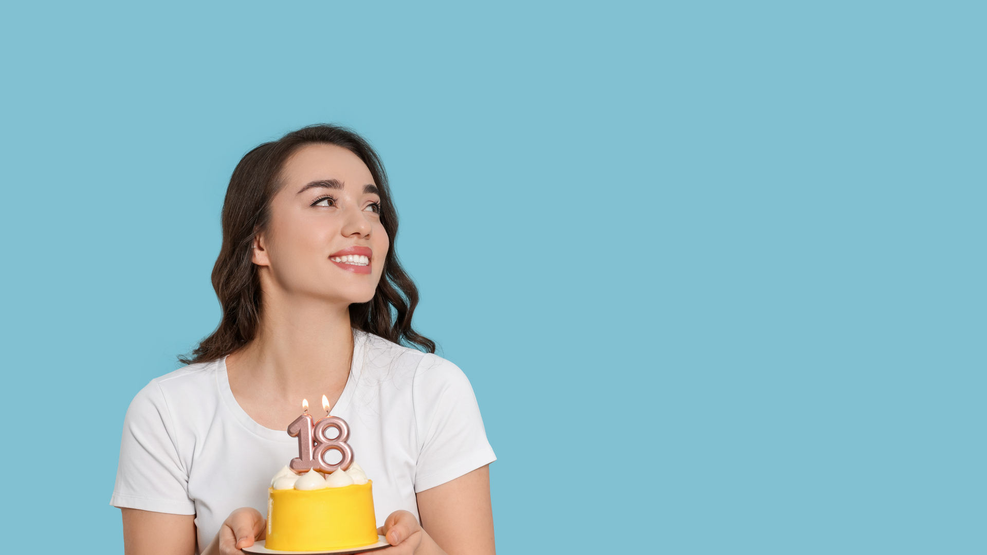 Coming of age party - 18th birthday. Woman holding delicious cake with number shaped candles on light blue background, space for text
