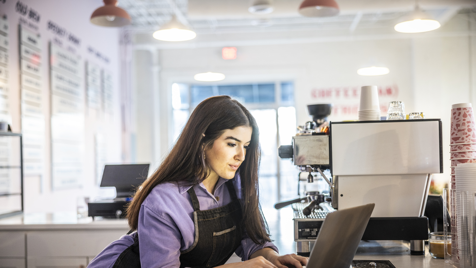 Female coffeeshop owner using laptop in modern coffeeshop