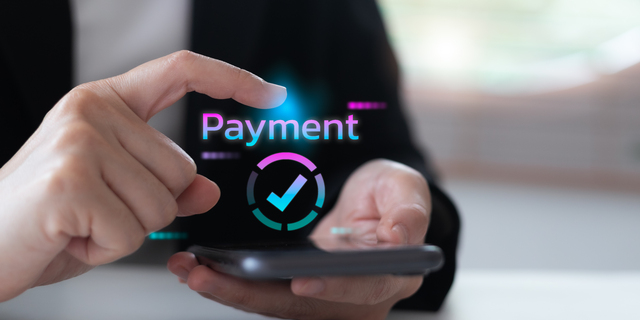 hand using a smartphone with a digital hologram payment confirmation icon. Concept of mobile wallet, online payment, fintech innovation, cashless society, financial technology, and secure transaction.