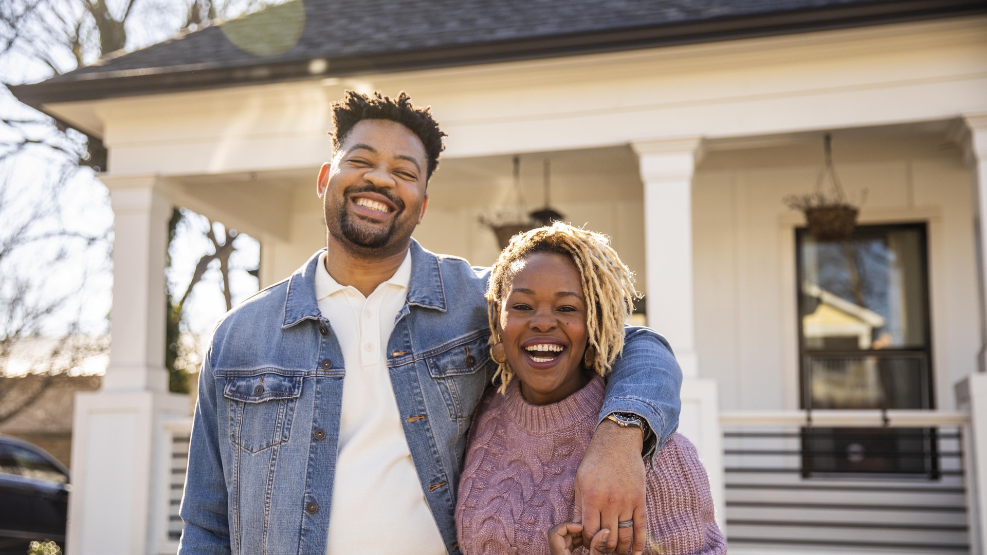 Portrait of husband and wife embracing in front of home