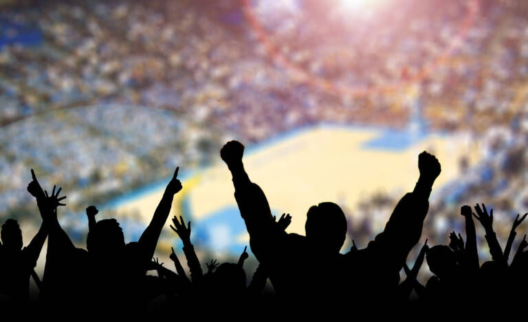 Basketball fans cheering at a basketball match - large crowd in an arena