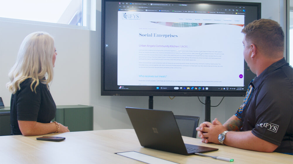 Photo of IFYS workers looking at a presentation that is connected to one worker's laptop