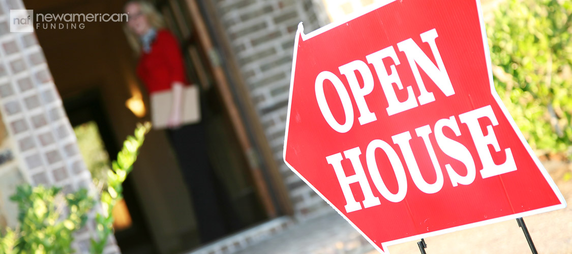 open house sign pointing to house entrance with a real estate agent waiting