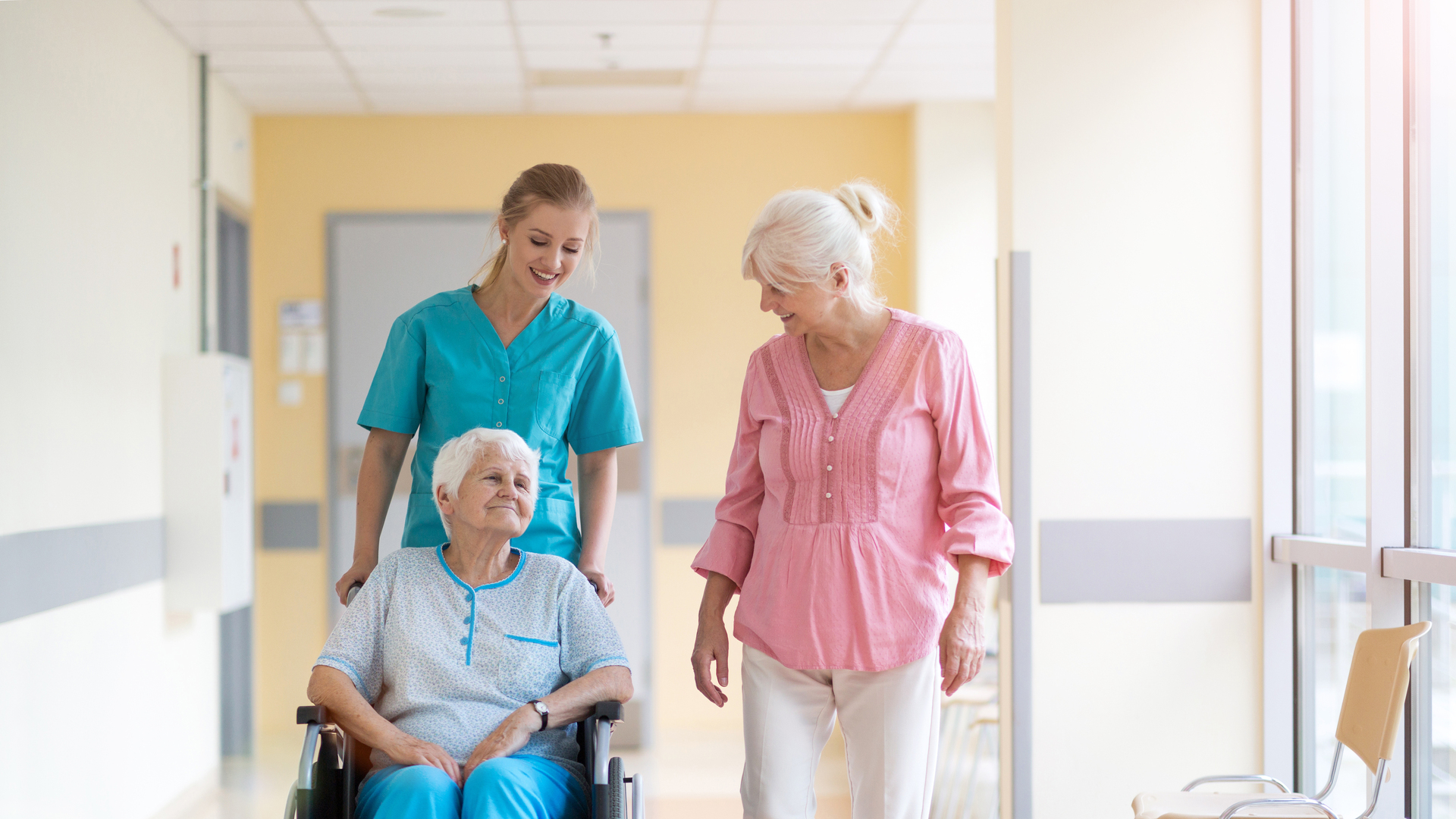 Elderly woman on wheelchair with her daughter and nurse