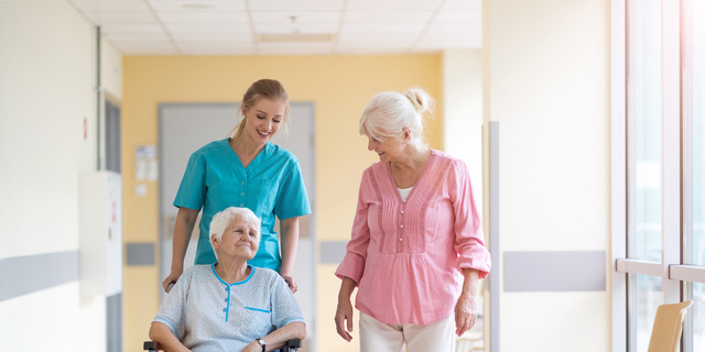 Elderly woman on wheelchair with her daughter and nurse