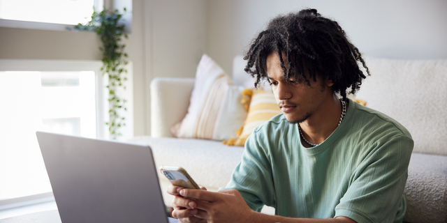 College student with laptop and mobile phone in dorm room