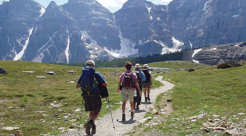 A group of Road Scholars hiking with towering mountains in the background