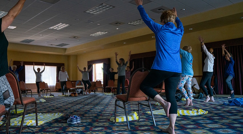 A group of Road Scholars raises their hands as part of a yoga class