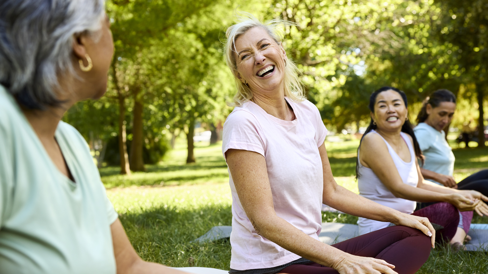 Happy woman enjoying yoga with friends in park