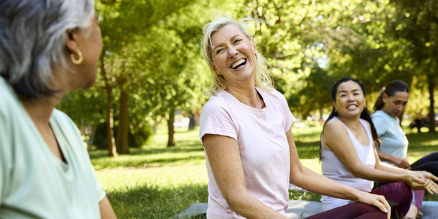 Happy woman enjoying yoga with friends in park